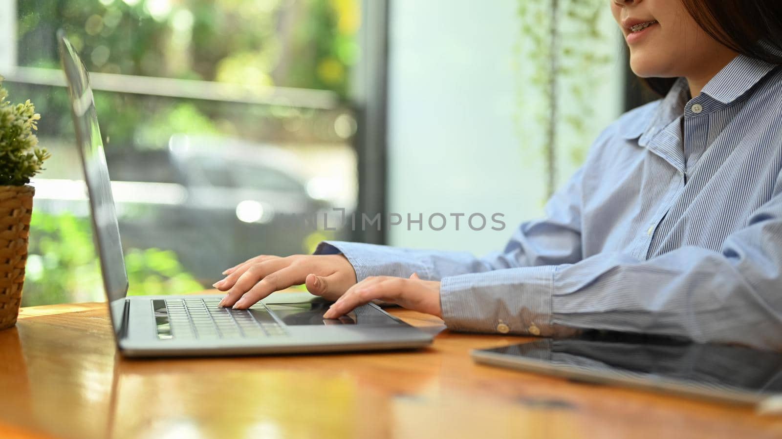 Side view young woman employee hands typing business email on her laptop computer.