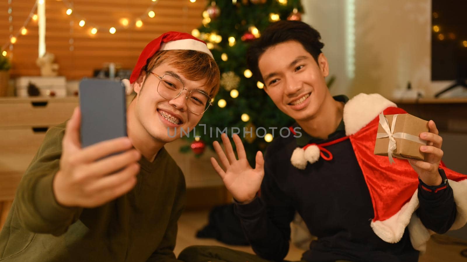 Happy friends using smartphone and take selfie in room decorated for celebrating New year and Christmas festive by prathanchorruangsak