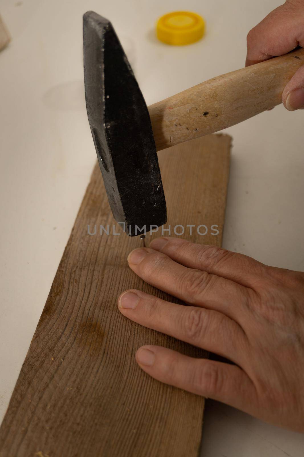 close-up of a woman's hands hammering a nail into a board.