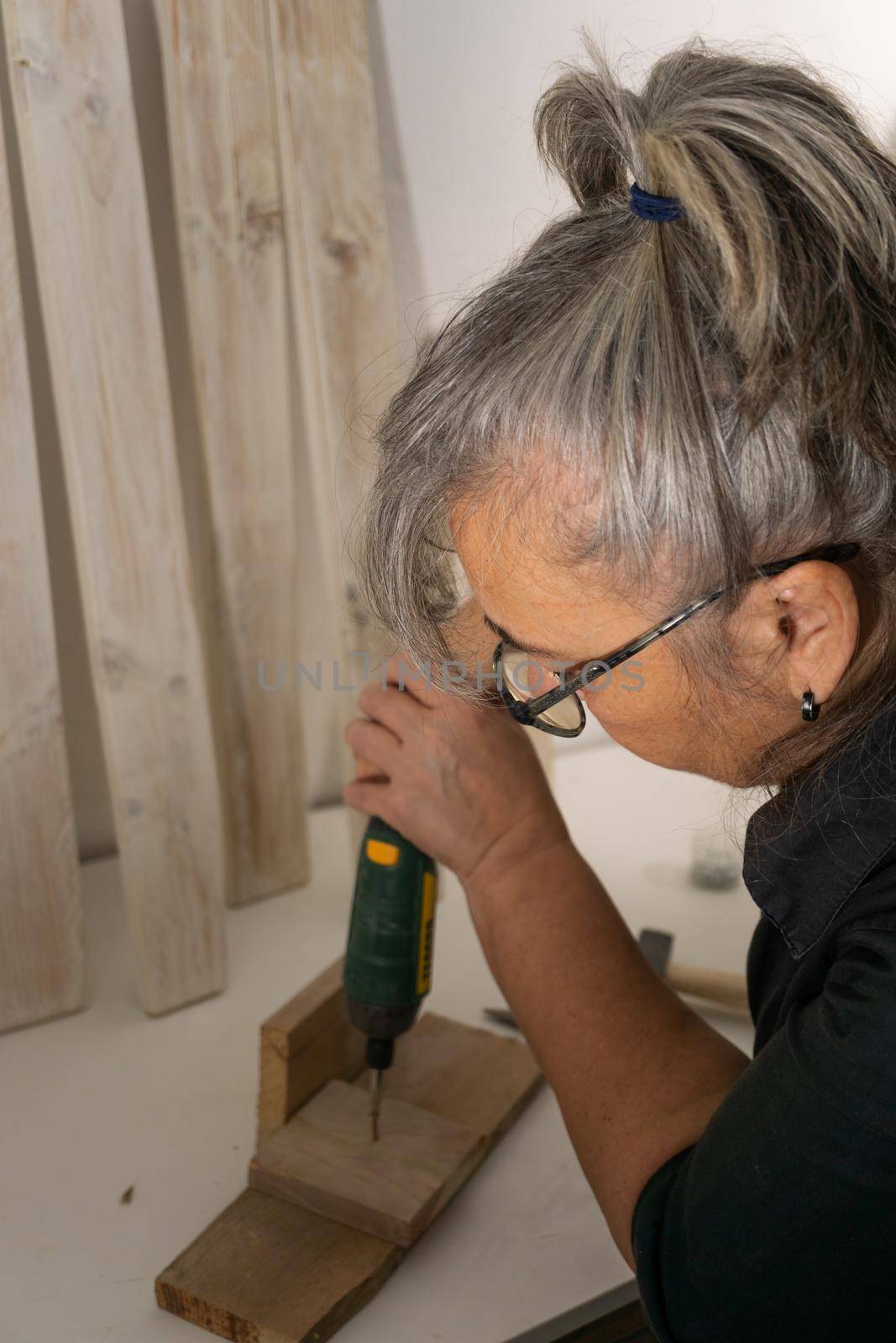 old woman working with power tools in her wood workshop