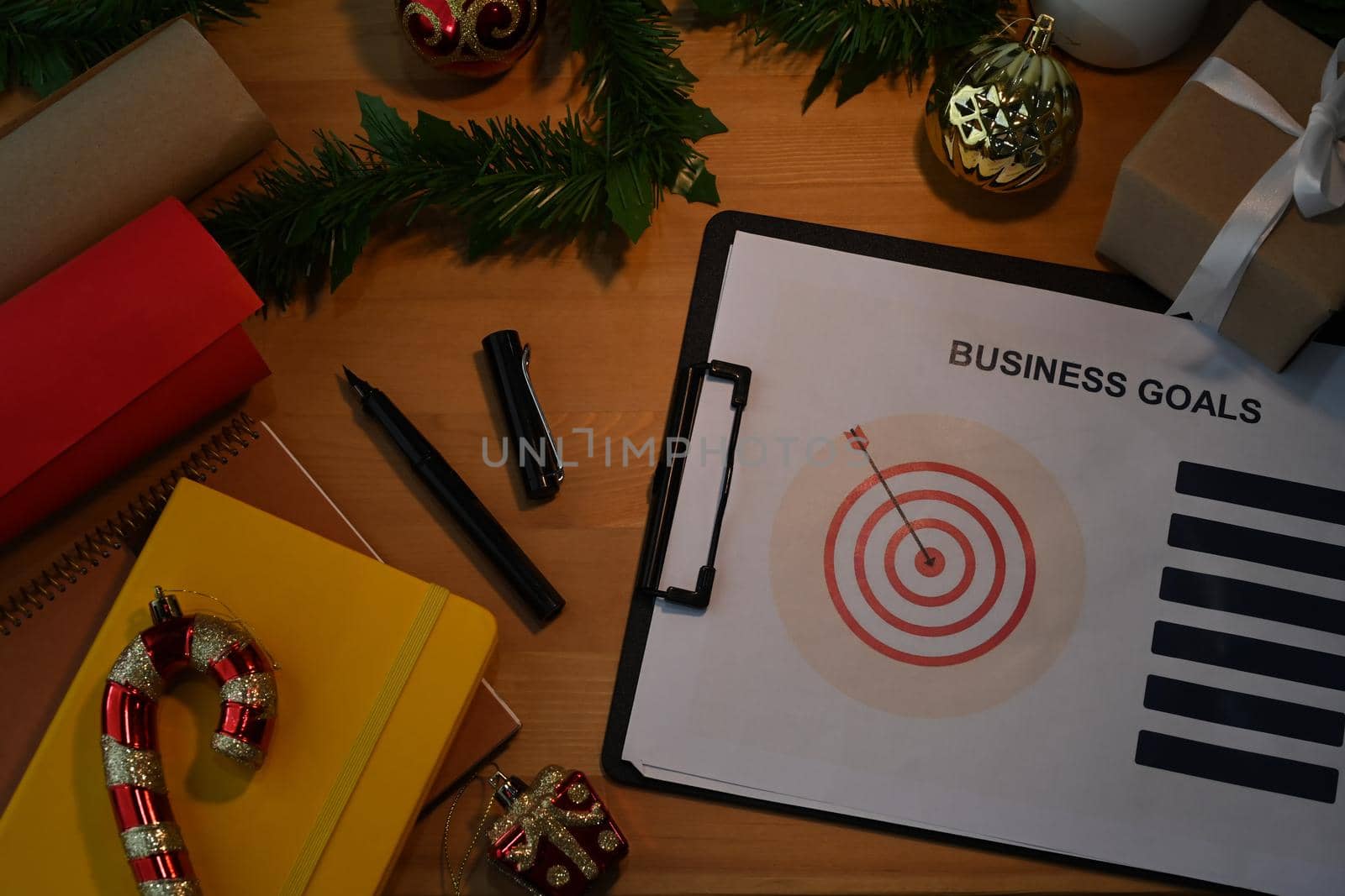 Above view of Wooden Christmas office desk with document, decoration and work supplies. Business Holidays Concept.