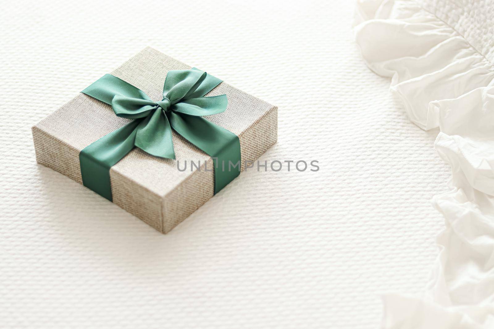 Holiday present and luxury online shopping delivery, wrapped linen gift box with green ribbon on bed in bedroom, chic countryside style, close-up