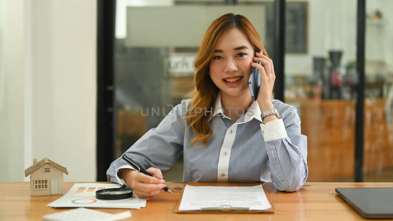 Attractive woman real estate broker having pleasant conversation, negotiations with her client on mobile phone.