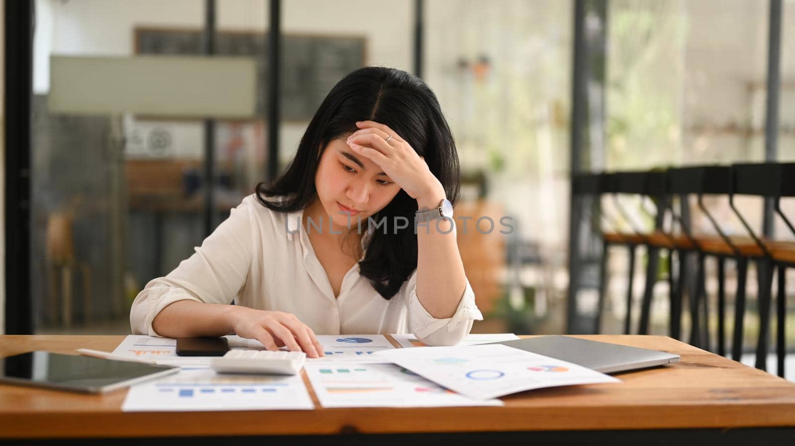 Stressed business woman suffering from migraine headache, considering financial problem solution.