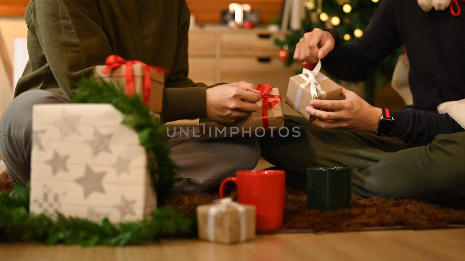 Cropped shot of two man celebrating Christmas, New Year at home together and exchange presents.