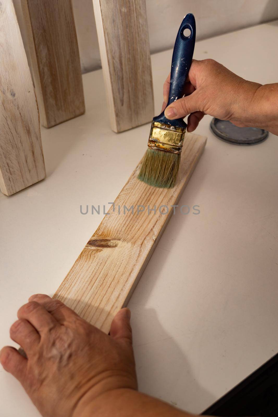 antique paintbrush painting wood with white paint in a workshop