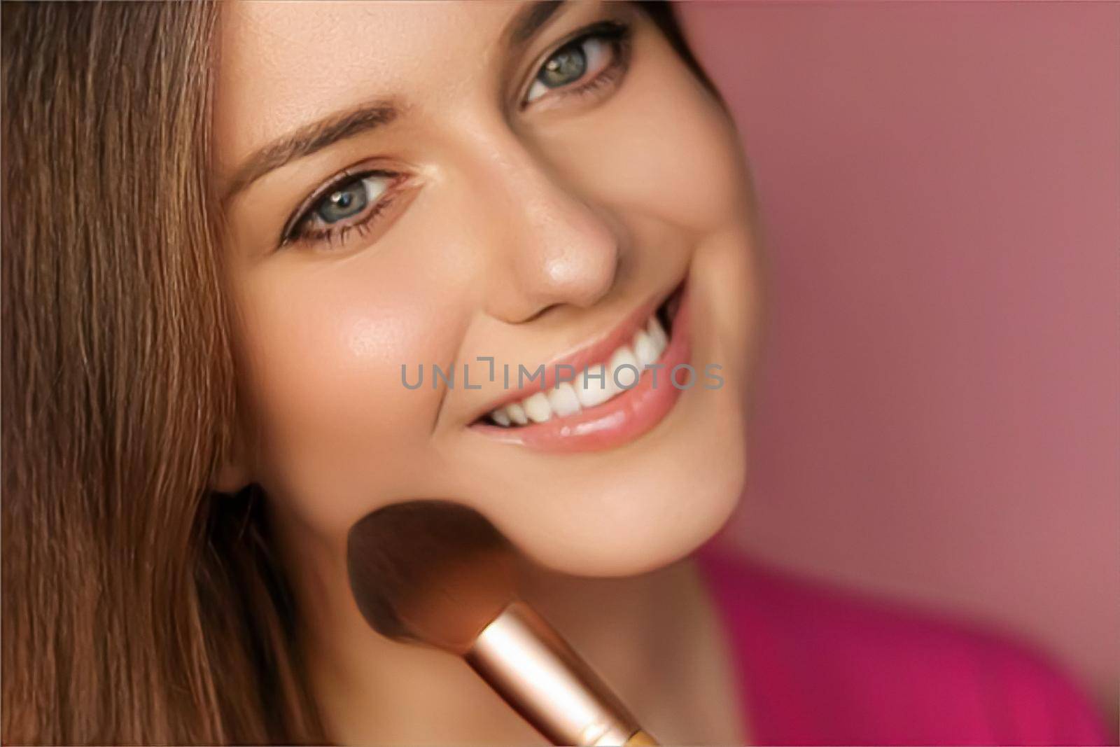 Beautiful young woman applying cosmetic powder product with make-up bamboo brush, beauty, makeup and skincare cosmetics model face portrait on pink background, closeup