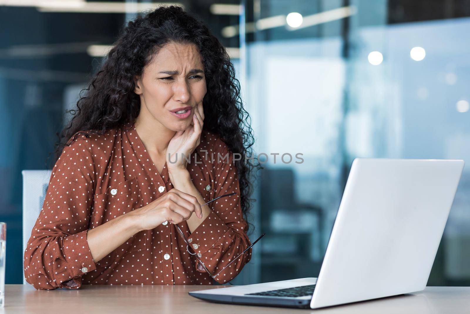 Beautiful business woman working inside office building, patient has severe toothache, worker uses laptop