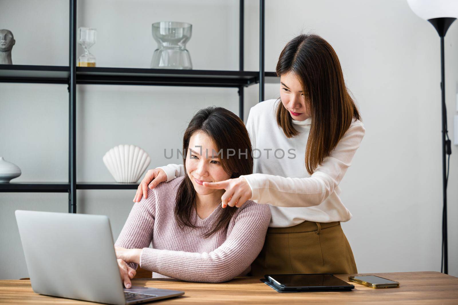Asian mother and teenage daughter looking at laptop computer at home office, happy family work together, middle age woman and teen they shoping online on computer
