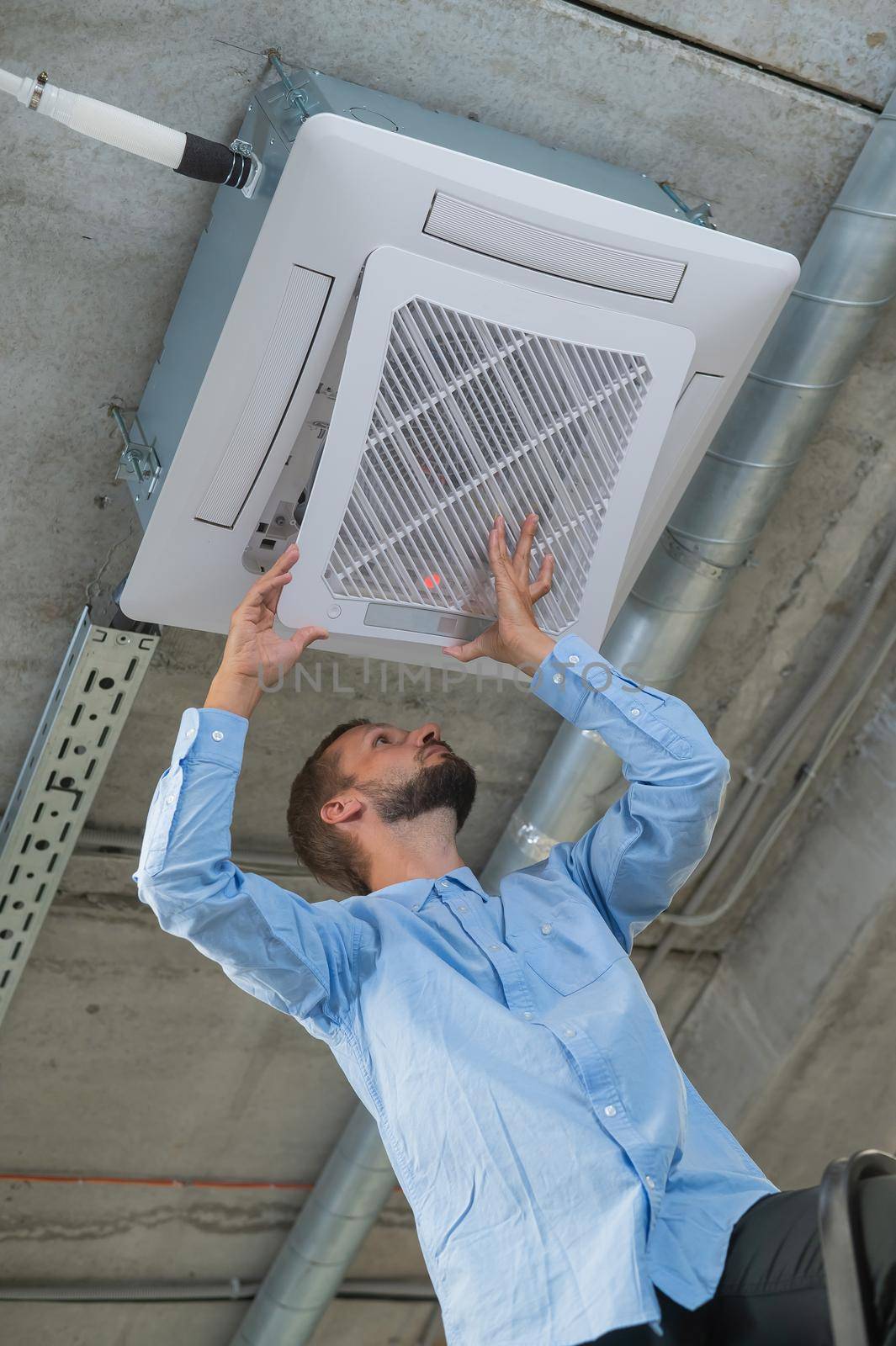 Caucasian bearded man repairing the air conditioner in the office