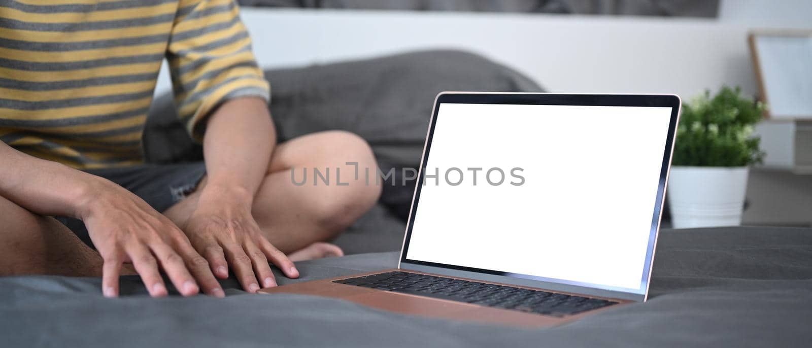 Mock up laptop computer with blank screen on bed.