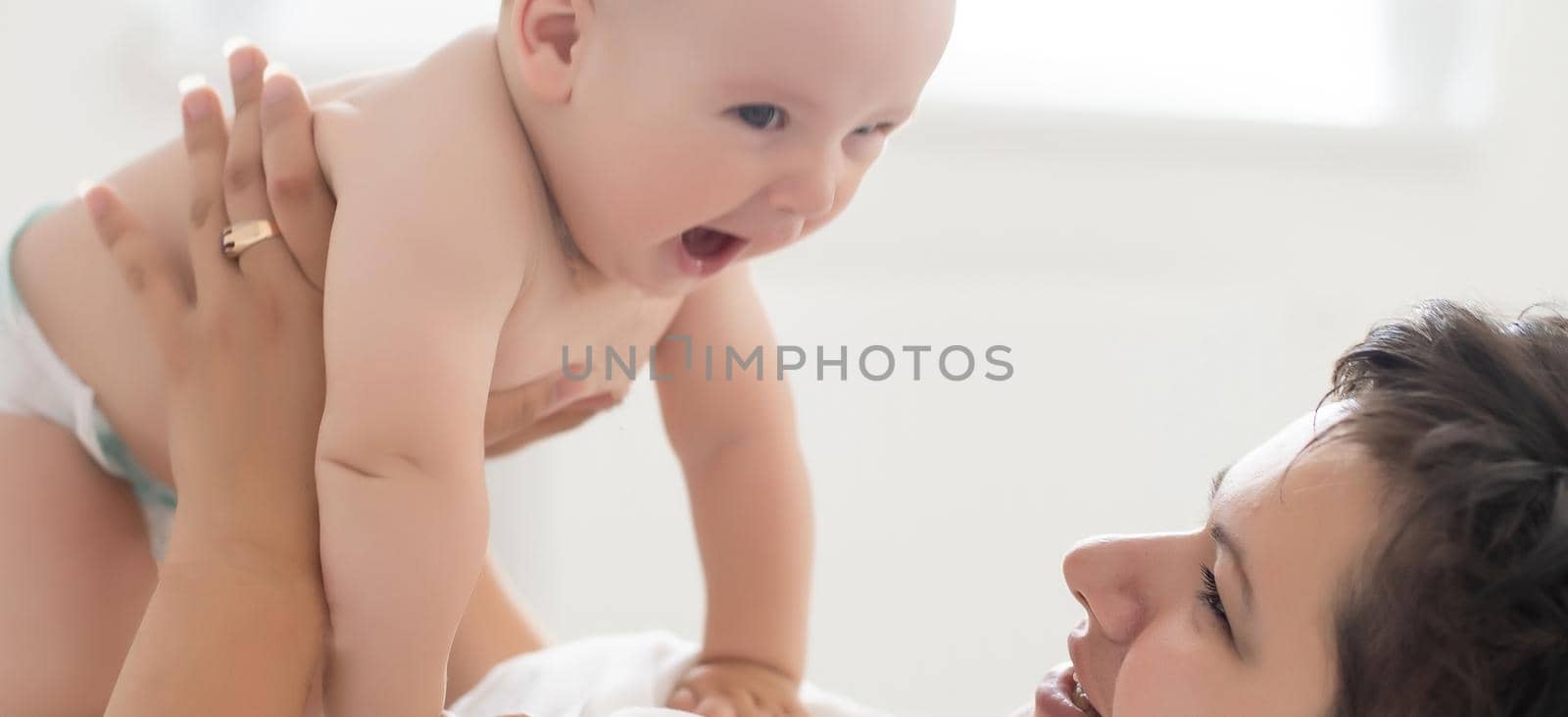 happy family. Mother and baby playing and smiling on bed.