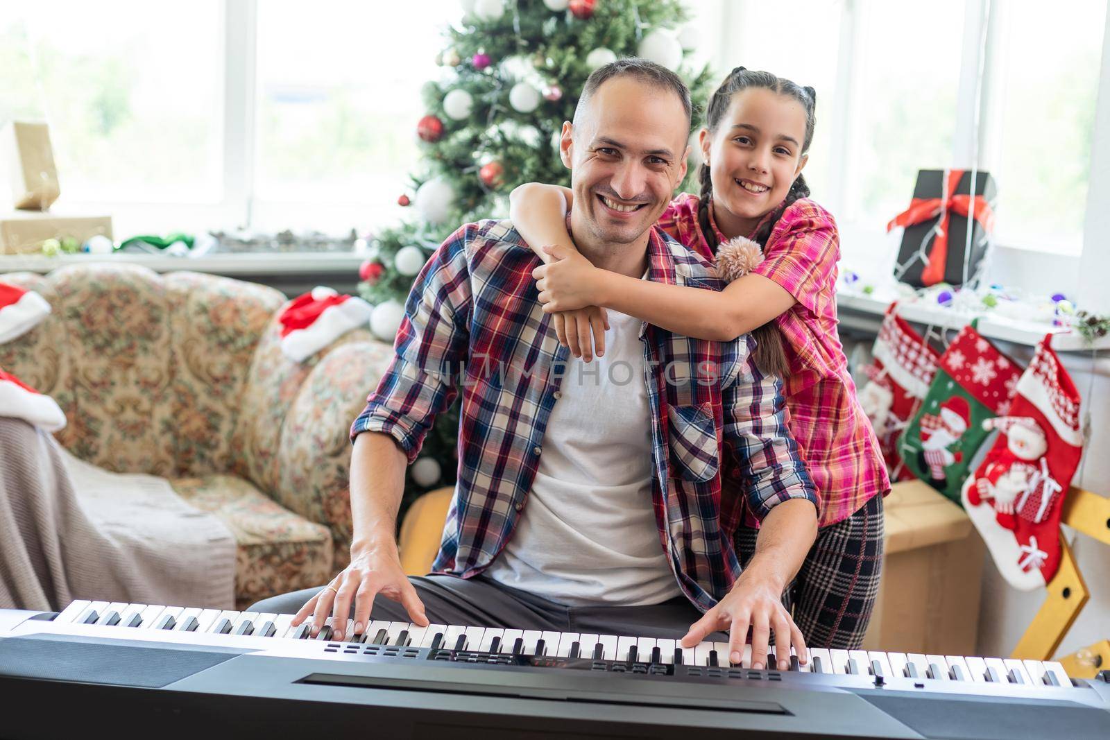 Smiling family on Christmas morning play music on piano