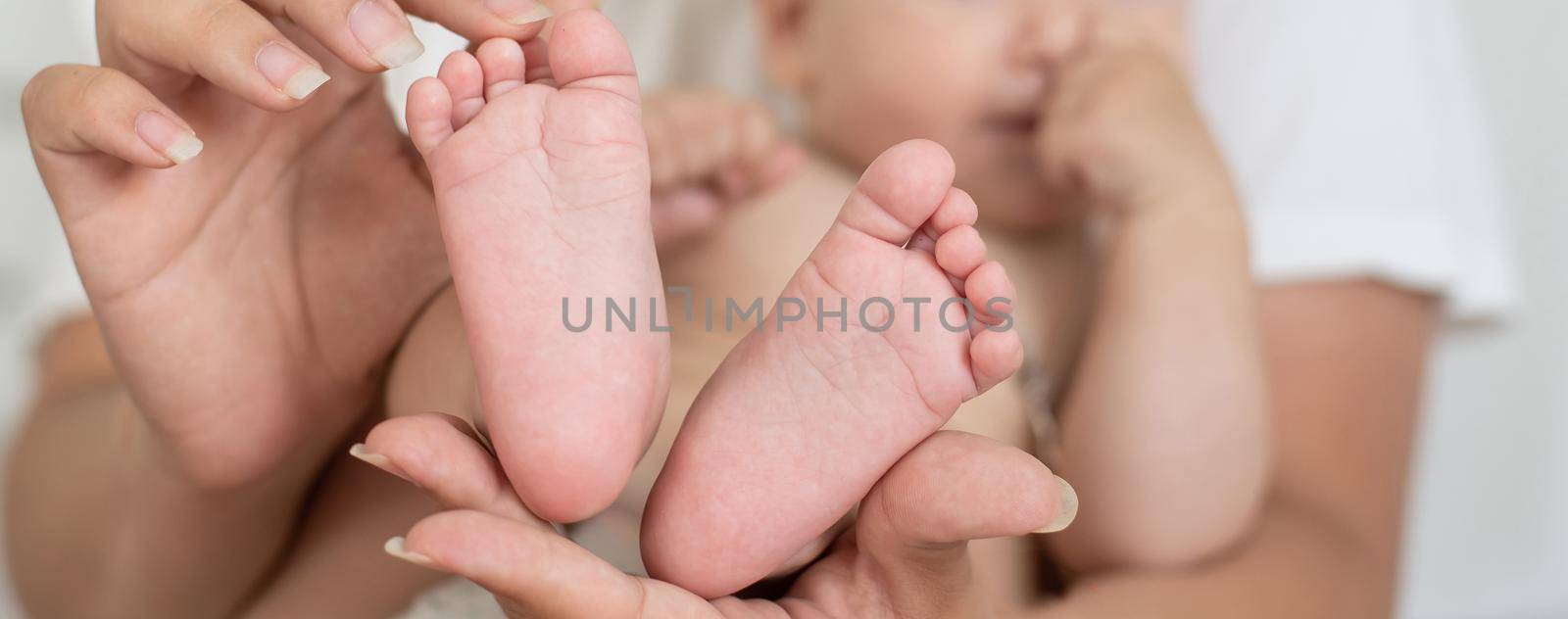 Parent holding in the hands feet of newborn baby by Andelov13