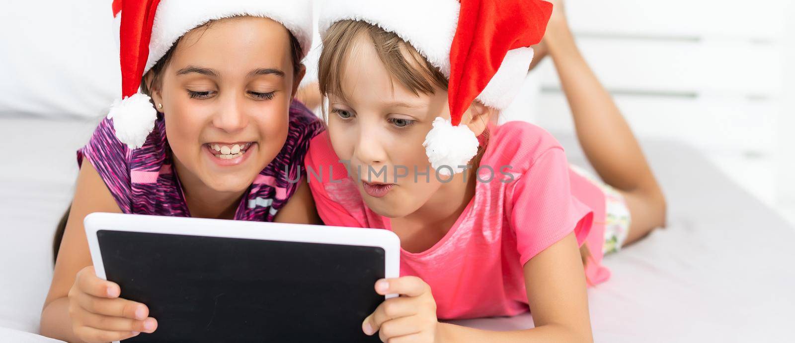 Excited small sister kids have fun browsing playing on modern tablet gadget together. Happy little girl children watch video on pad device, enjoy family winter holidays at home. by Andelov13