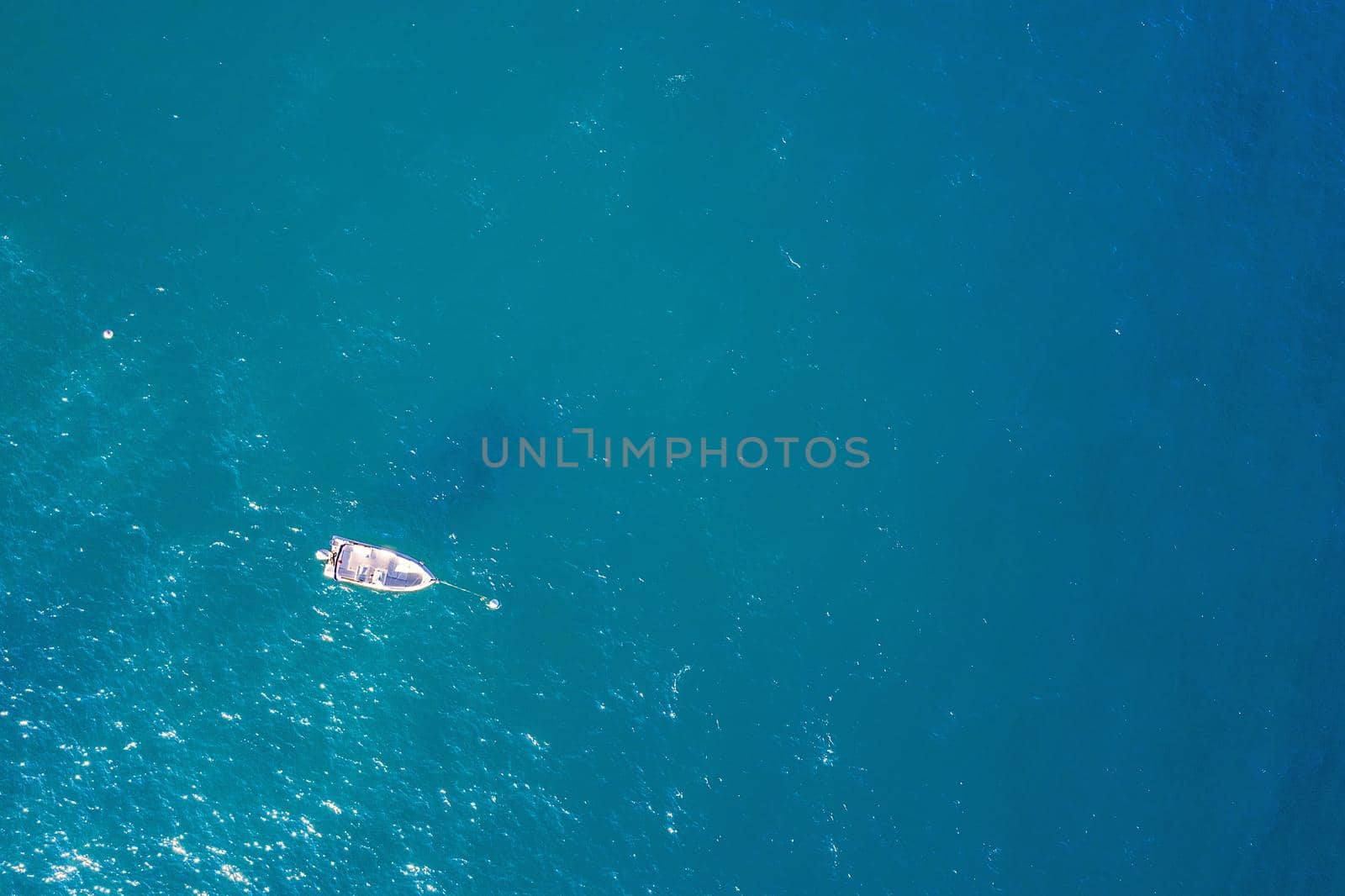 top view of a white boat anchored in the blue sea in a tropical beach with turquoise waters. concept of adventure lifestyle and water sports in summer holiday