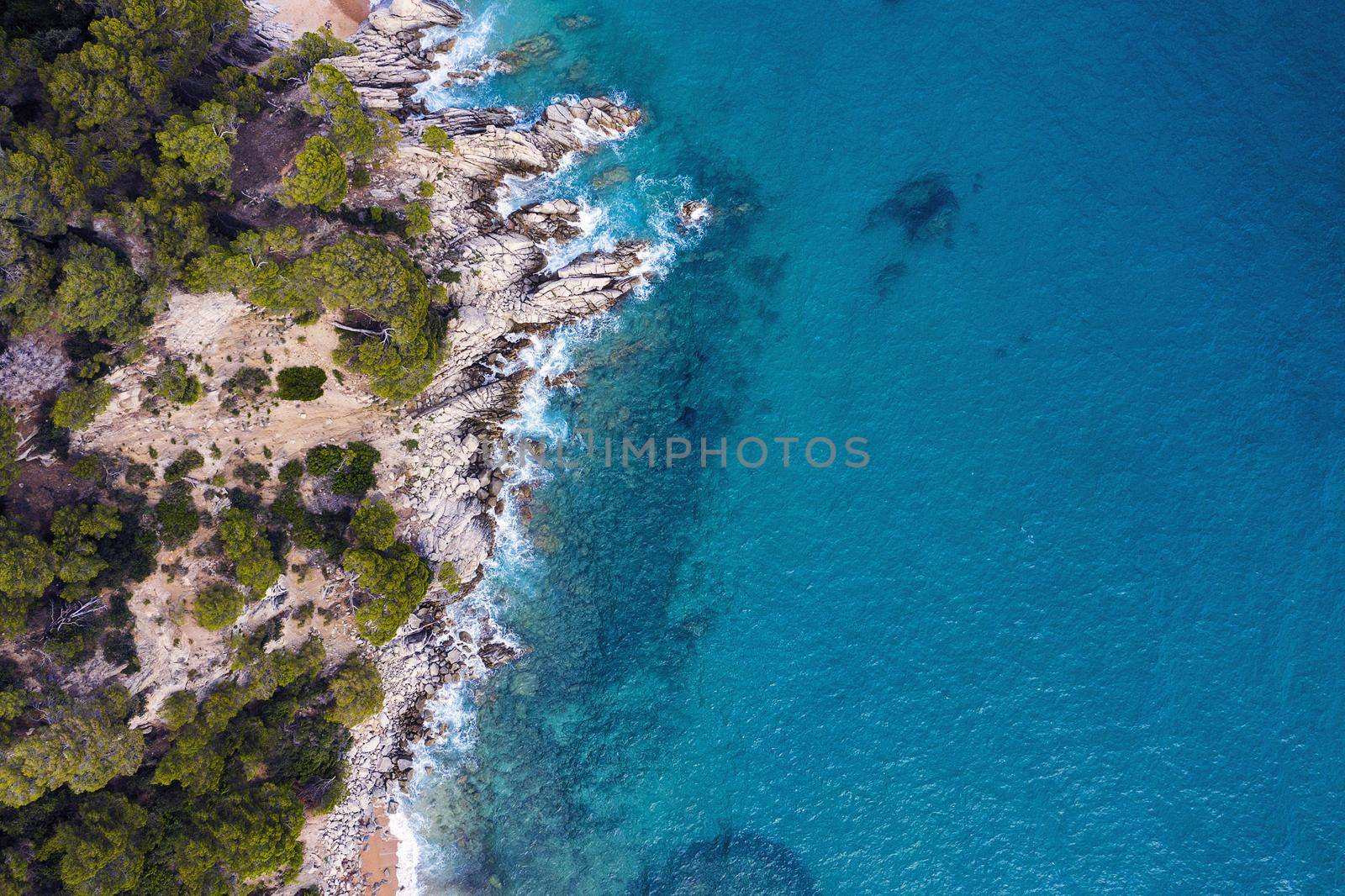 aerial top view of a clear ocean with beautiful sea waves hitting on the cliffs of the island coast with spray and foam, concept of adventure lifestyle and summer holidays in the wilderness