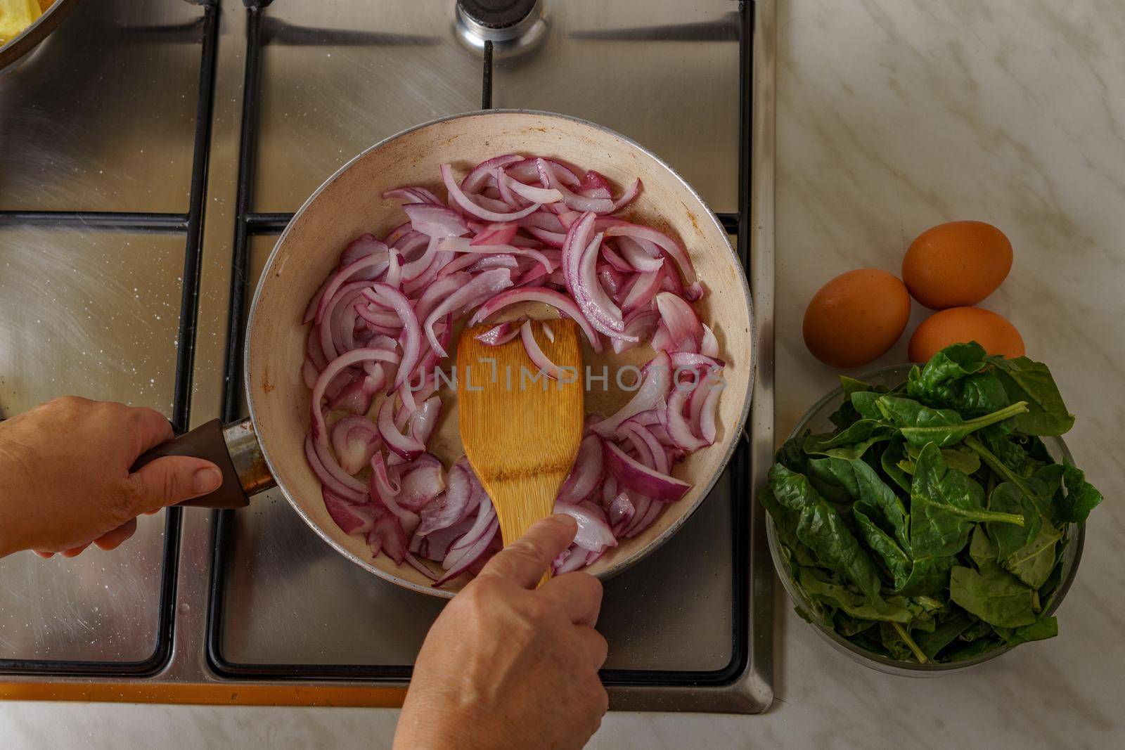 woman pouring shallot onion into a pan with boiling oil by joseantona