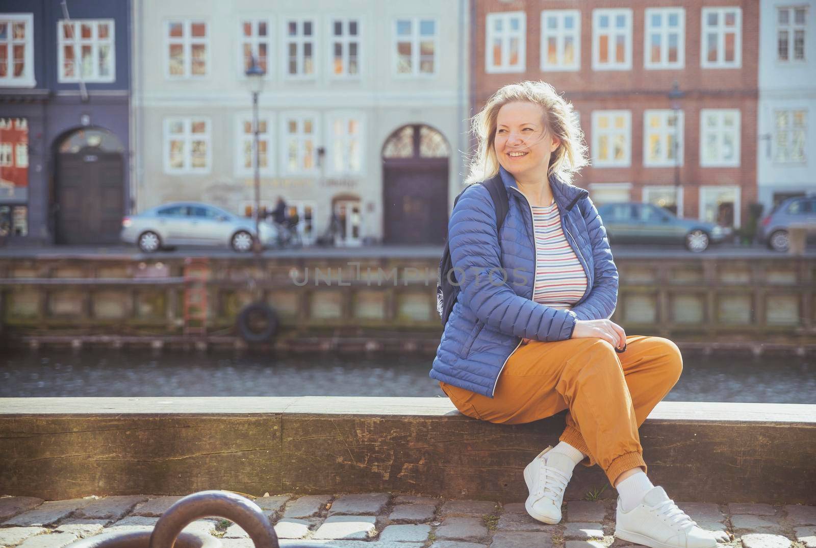 Blonde girl relaxing on the waterfront in Nyhavn in Copenhagen.