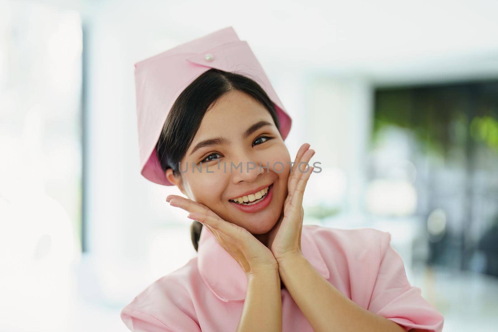 Portrait of a young nurse in a pink dress smiling happily by Manastrong