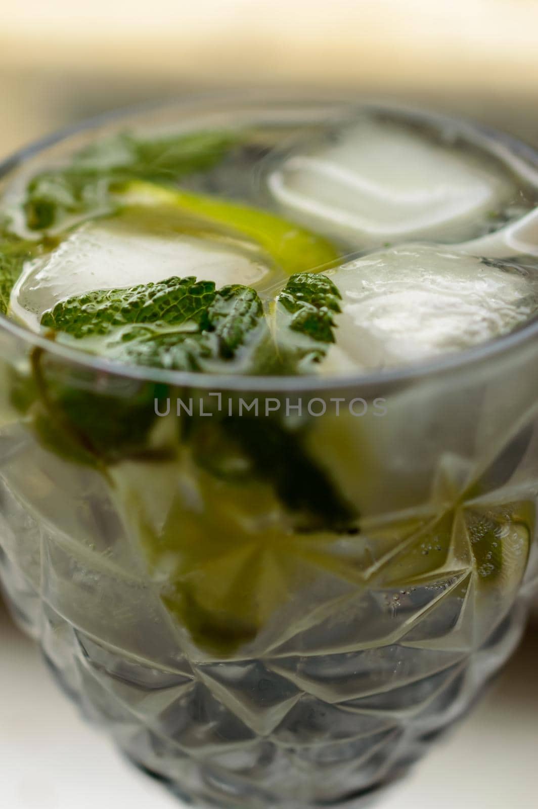 Close up photo of a fresh alcoholic mojito with an ice, lime and mint in the pretty goblet. Background picture. High quality photo