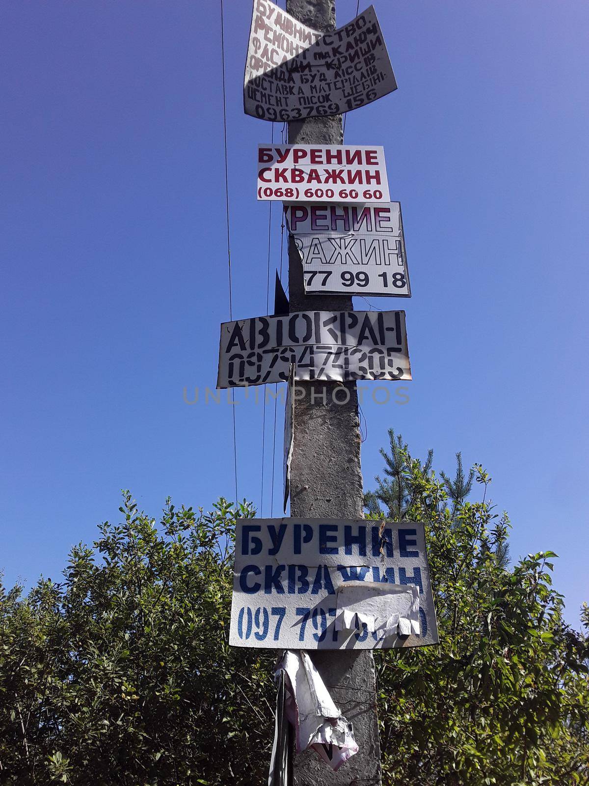 KIEV OBLAST, UKRAINE - SEPTEMBER 12, 2022: Construction service announcements on a pole by architectphd