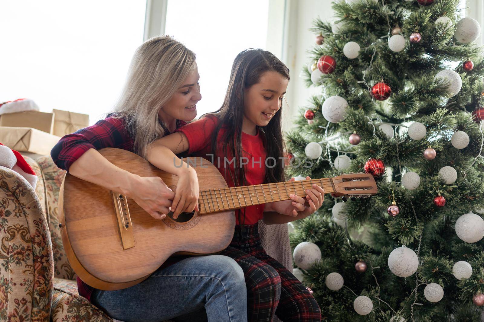 Little girl and her mother decorating Christmas tree at home