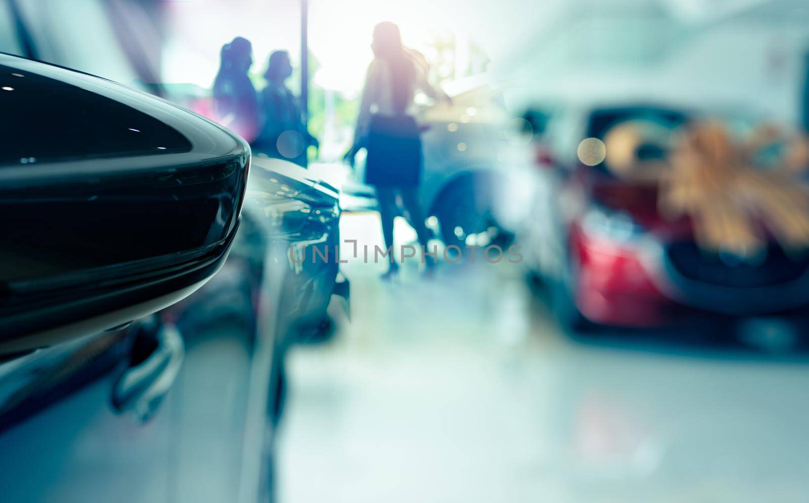 Selective side mirror car on blur saleswoman and customer in modern luxury showroom. Car dealership office concept. Dealer agent business. Automobile leasing service. Dealer company. New car purchase.