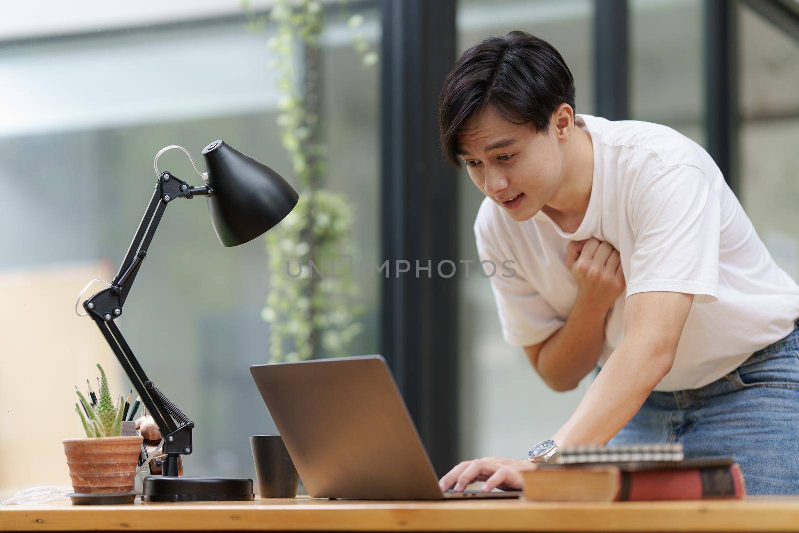 Asian man using laptop computer shocking while have a bad news.