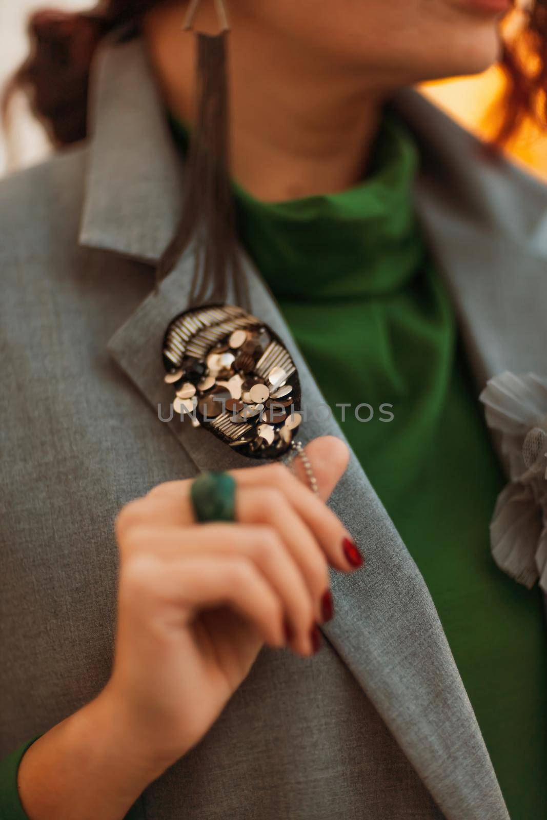 Outdoor fashion portrait of an elegant fashionable brunette model in a beret, green dress and a gray waistcoat posing at sunset in a european city in autumn