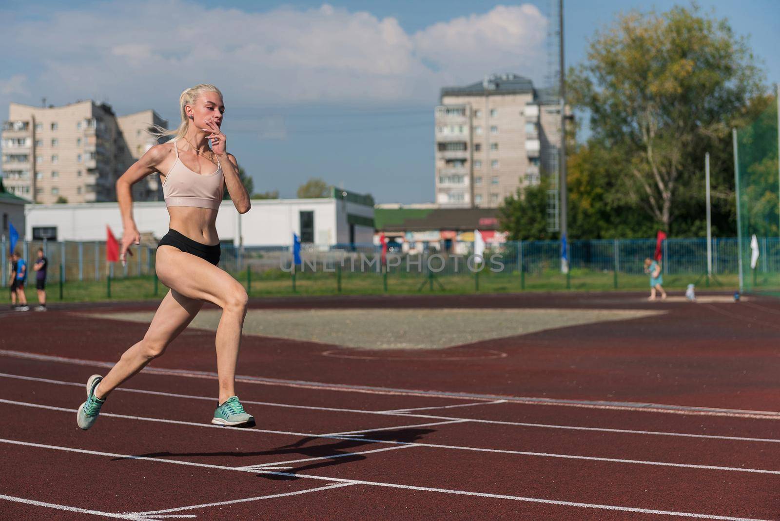 Young woman running on the running track at the stadium outdoors