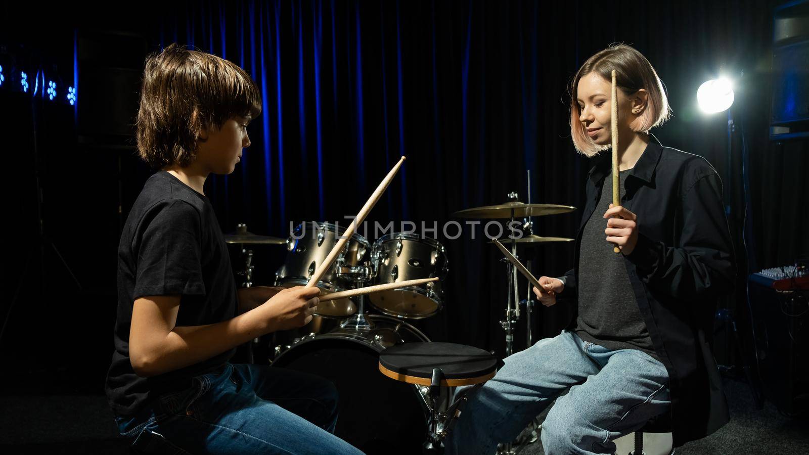 Young woman teaching boy to play drums