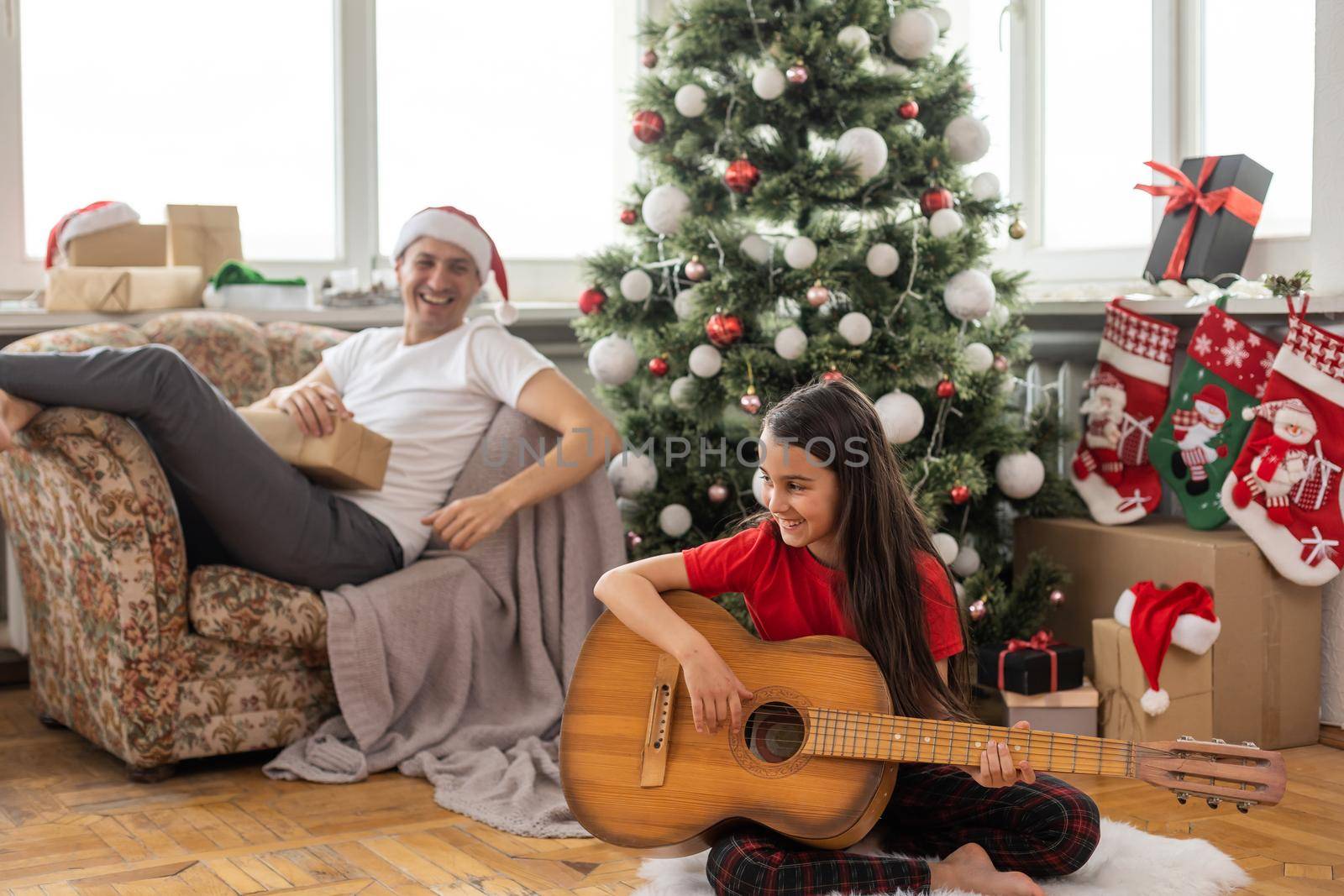 Full body photo of young cheerful family happy positive smile little girl play guitar decoration holiday indoors. by Andelov13