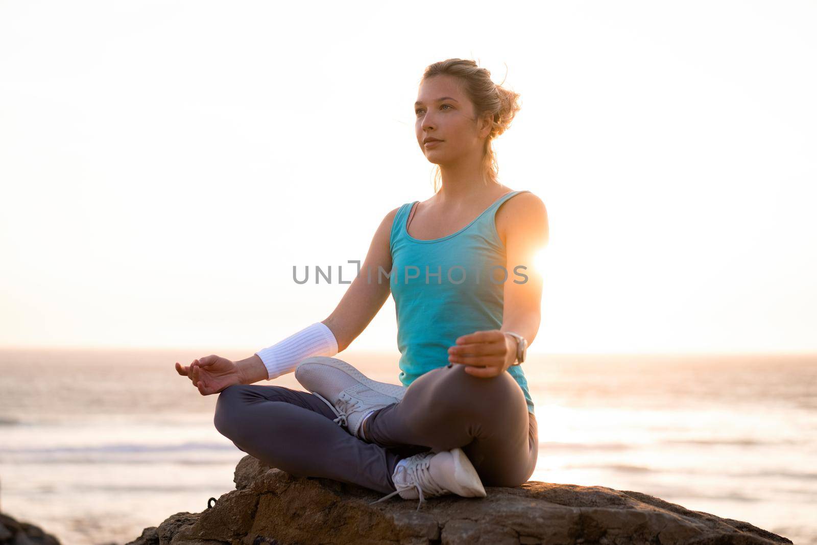 Woman practice yoga lotus pose to meditation with summer vacation rocky beach happiness and relaxation. Calm female exercise with yoga meditate ocean beach with sunset golden time. Zen Mental health