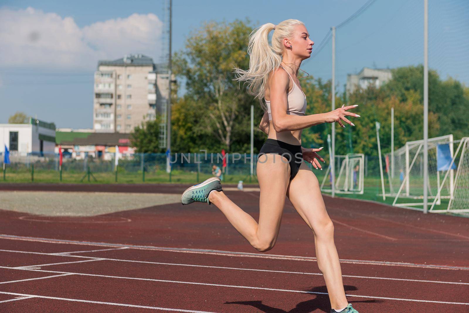 Young woman running on the running track at the stadium outdoors