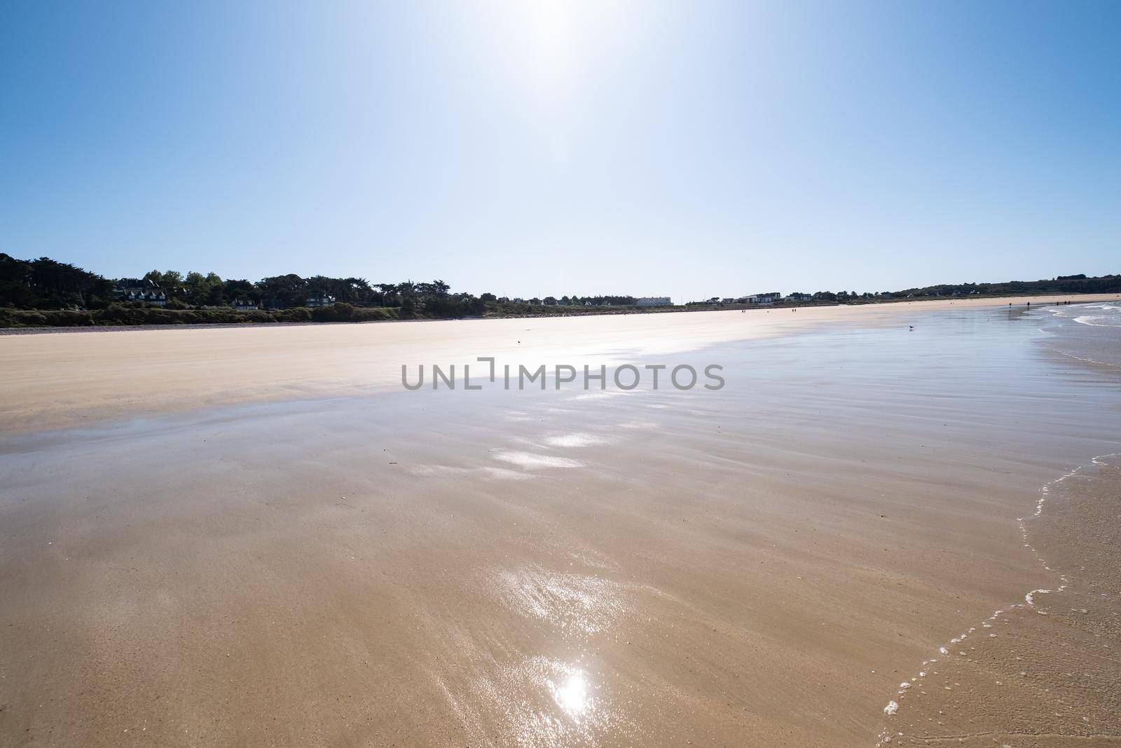 Large sandy beach in the town of "Sables d'or les pins" in Brittany at low tide in summer.