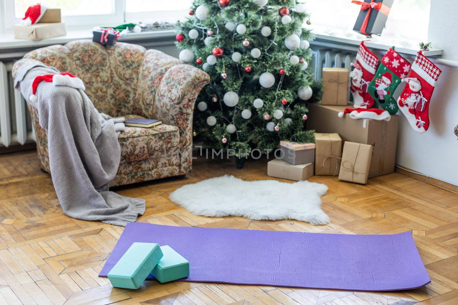 A blue yoga mat on a marble floor in a big living room. Christmas tree is on the background.