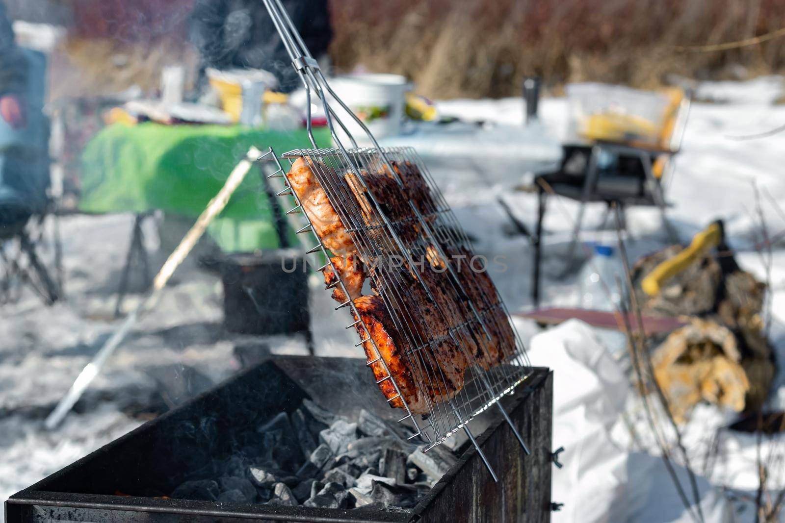 Winter barbecue party outdoors, grill steak meat over hot coals in BBQ at campsite cookout, close up view, camping mood