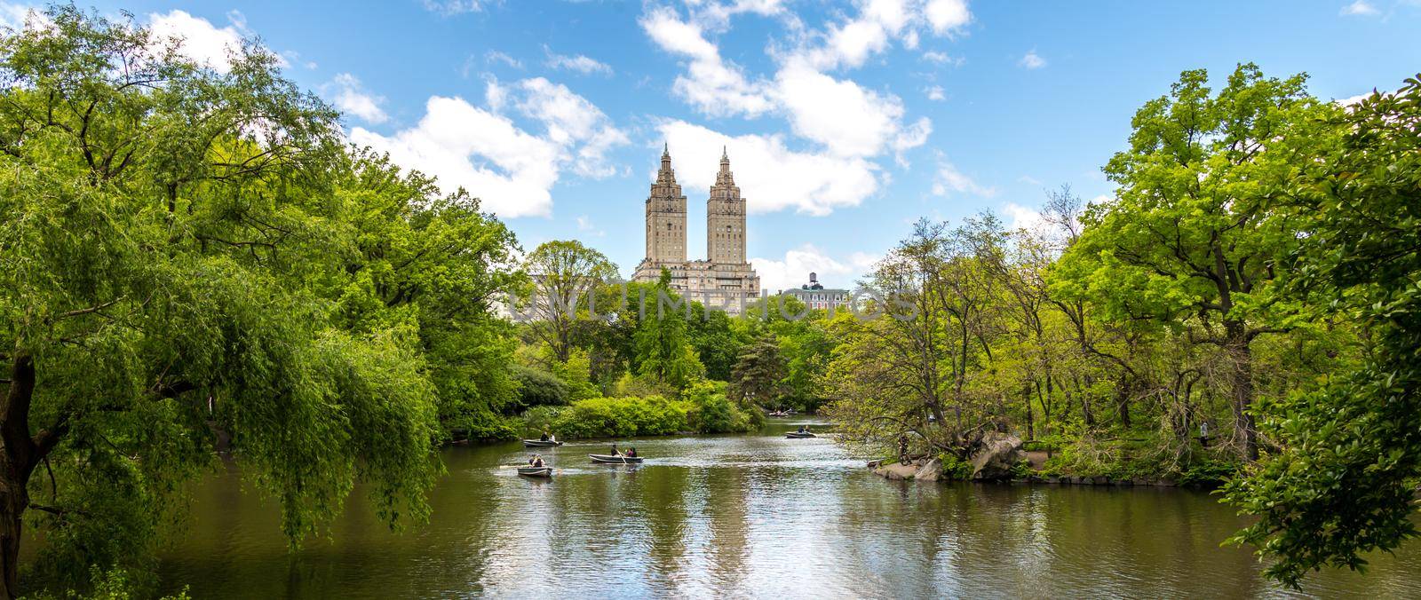 New york, USA - May 15, 2019: Row boats in lake in Central Park with Eldorado building in distance, Manhattan, New York city, USA by Mariakray