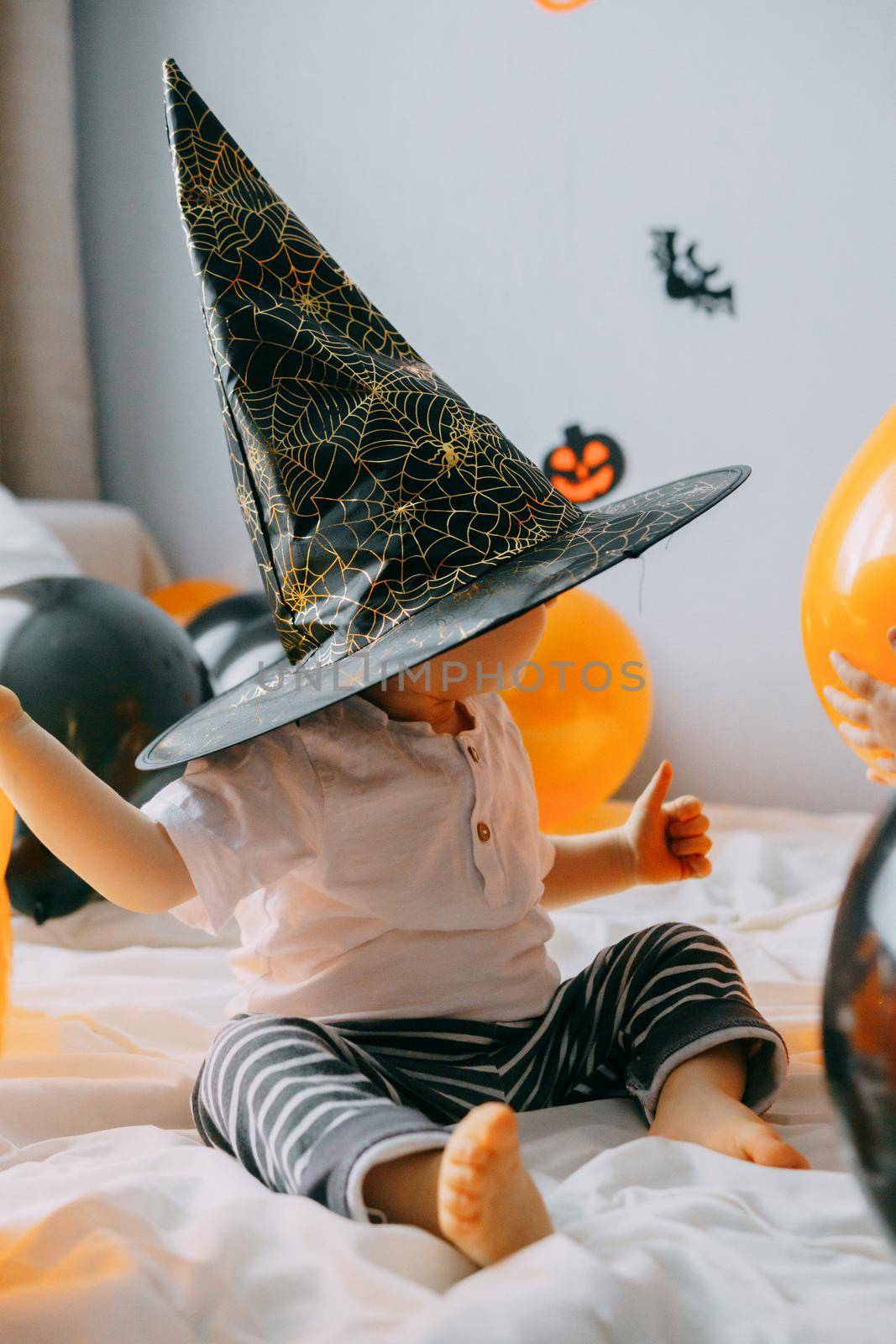 Children's Halloween - a boy in a witch hat and a carnival costume with airy orange and black balloons at home. Ready to celebrate Halloween by Annu1tochka