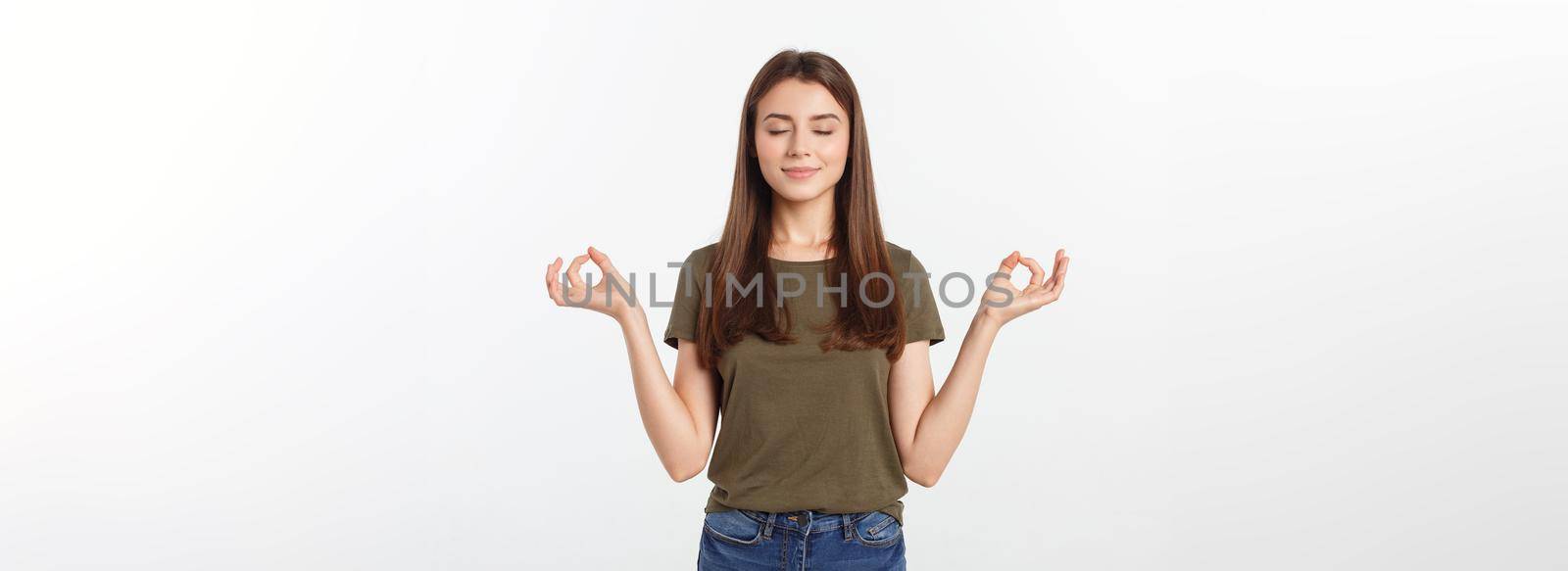 Beautiful young woman in yoga position and meditating isolated over gray background.