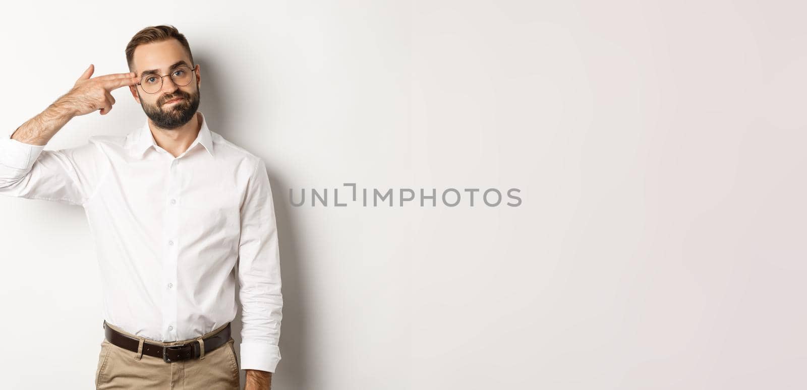 Tired man making shooting in head and looking bored, standing distressed over white background.