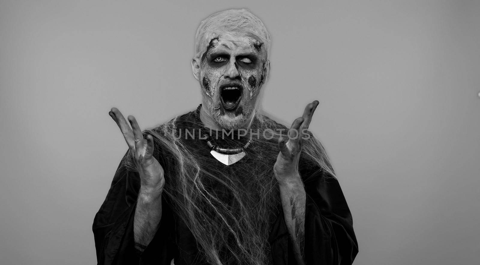 Dissatisfied frightening man with Halloween zombie bloody wounded makeup asking reason of failure, expressing disbelief irritation, feeling bored, disappointed in result, bad news. Sinister undead guy