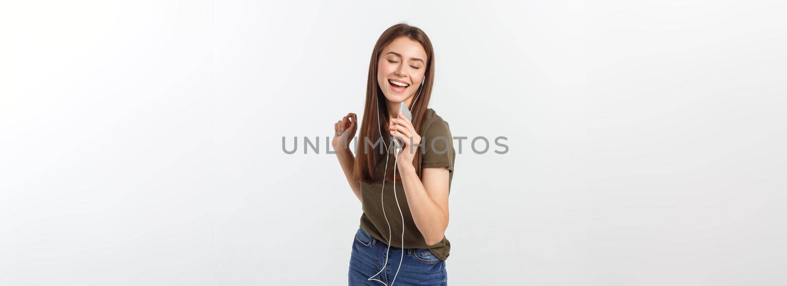Portrait of a cheerful cute woman listening music in headphones and dancing isolated on a white background