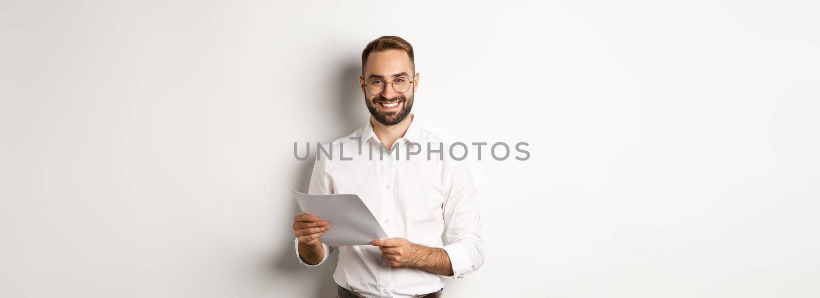 Employer looking satisfied with work, reading documents and smiling pleased, standing over white background.