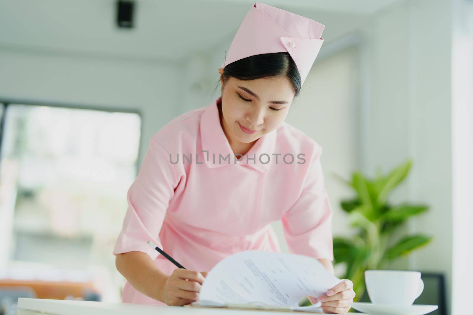 Portrait of a young Asian nurse looking at patient documents to analyze symptoms before sending them to the doctor for examination.