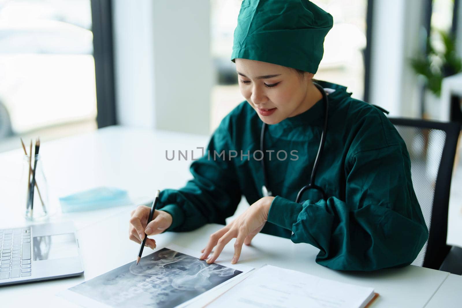 Portrait of an Asian doctor looking at patient X-ray film to analyze the abnormality of the client's body.