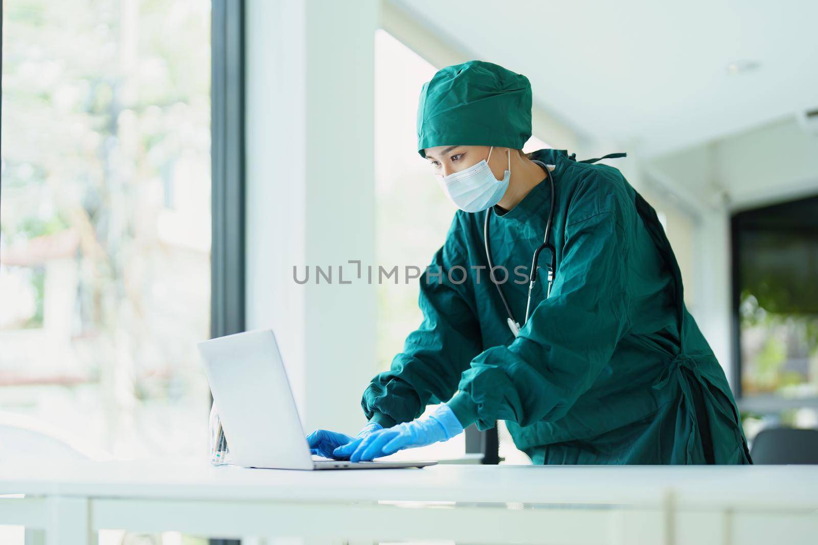 Portrait of an Asian doctor using a computer to look at patient data to analyze symptoms before treatment.