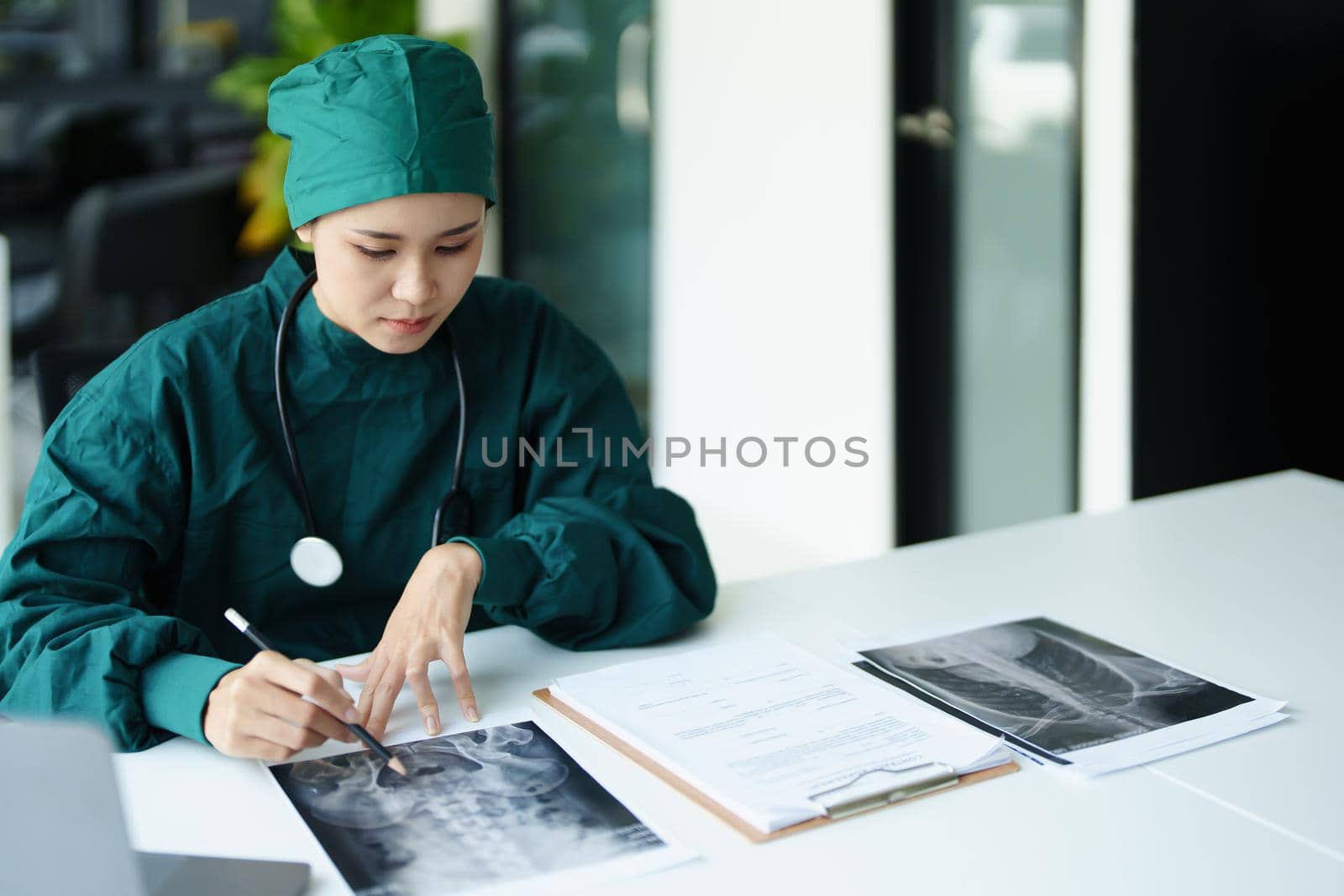 Portrait of an Asian doctor looking at patient X-ray film to analyze the abnormality of the client's body.