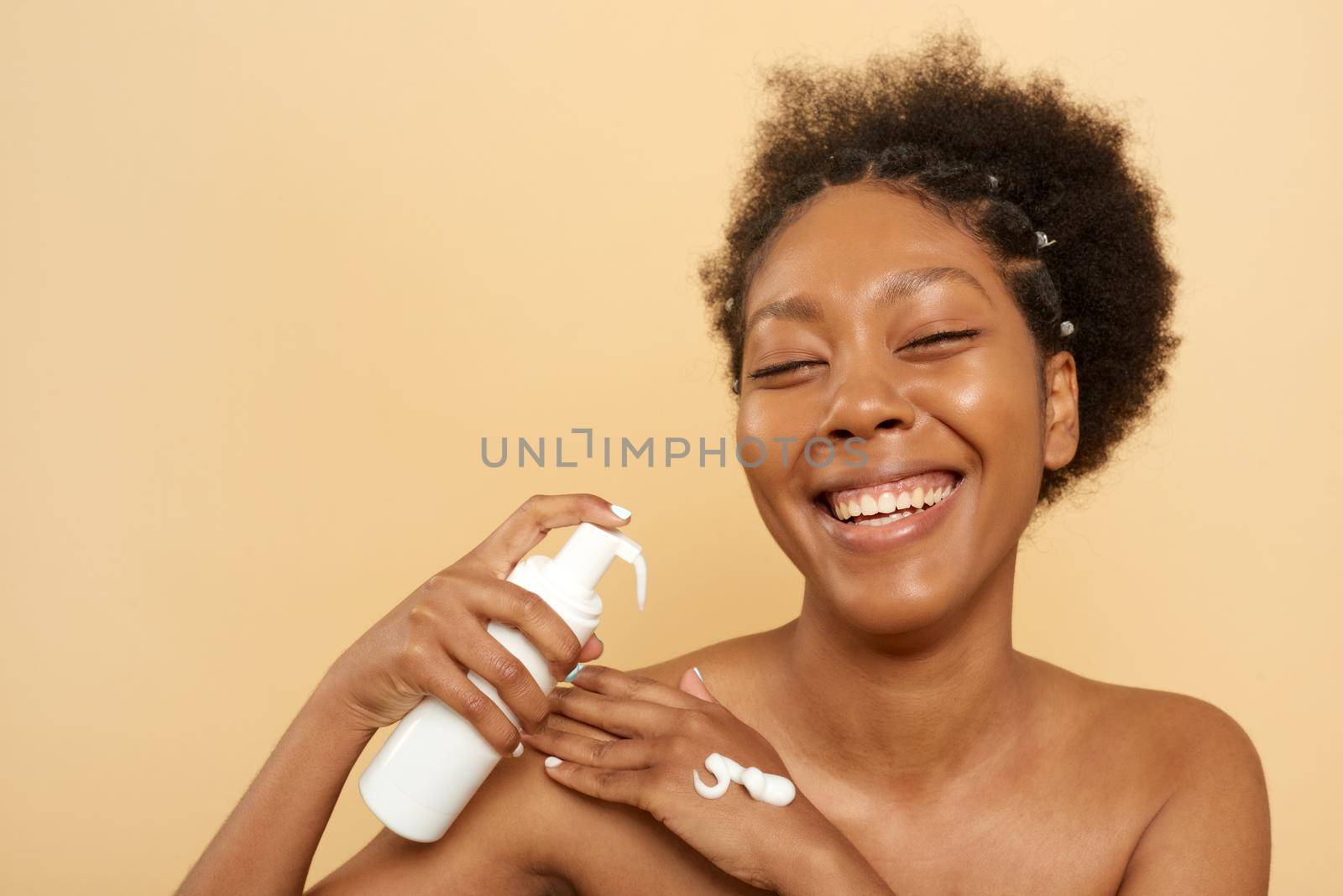 Cheerful african american woman with cleansing foam bottle in studio